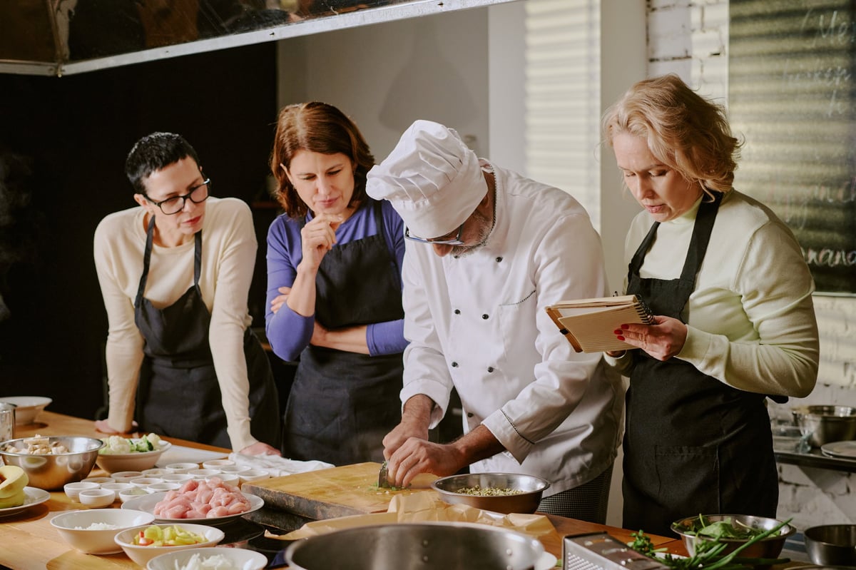 Cocinero enseñando técnicas culinarias a principiantes en clase de cocina