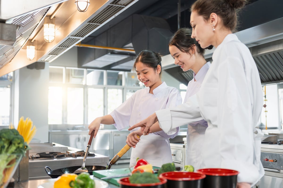 Estudiantes aprendiendo técnicas de cocina con instructor profesional